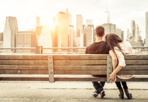 couple relaxing on New york bench in front of the skyline at sunset