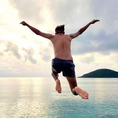 Man taking a chance jumping off of a cliff into the ocean