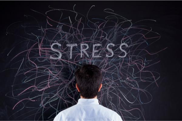 Stress Concept with the word STRESS written on the blackboard and a man standing in front of it facing the blackboard